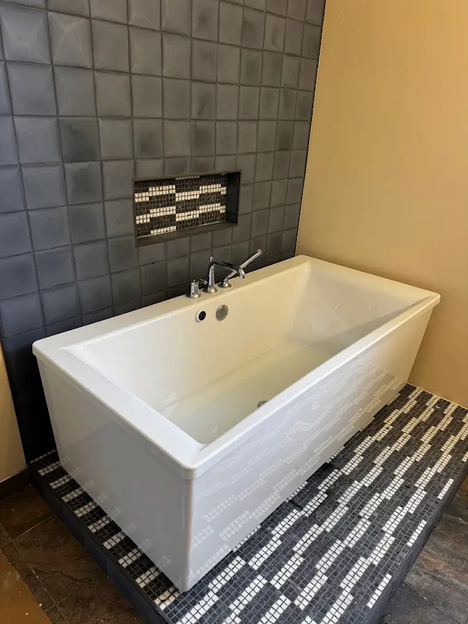 Freestanding bathtub with a dark tile accent wall and mosaic floor
