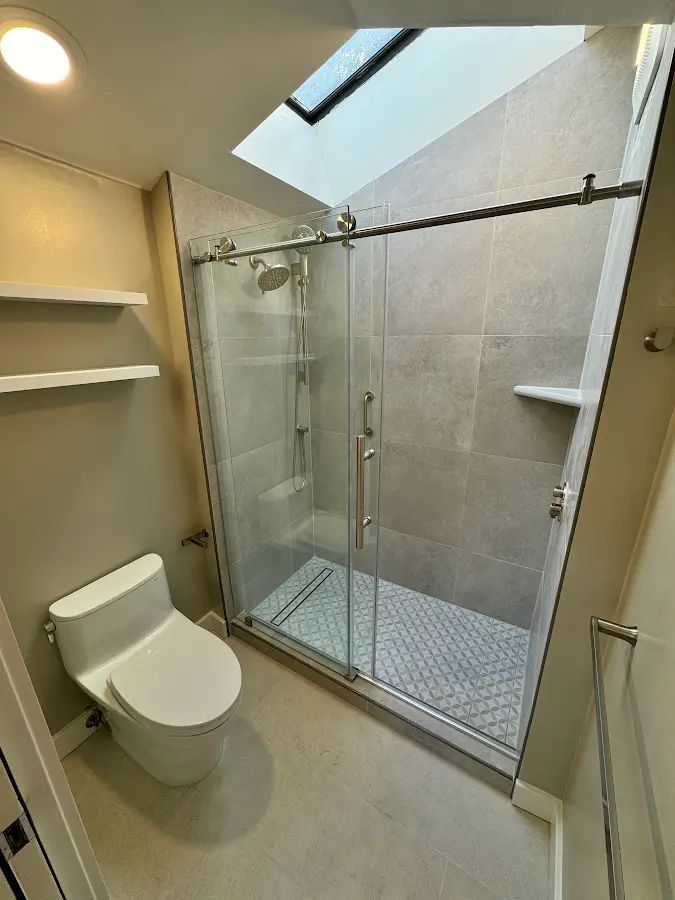 Complete bathroom view with a glass shower enclosure beneath a skylight