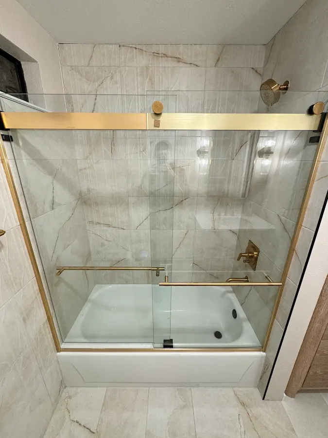 Marble-look tiled shower with a brass-framed glass enclosure