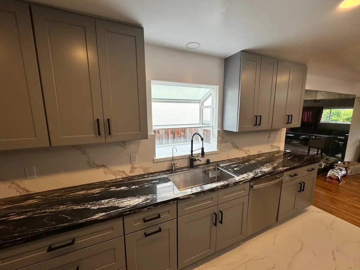 Kitchen sink, gray cabinets and dark stone countertop